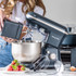 Grey stand mixer with large stainless steel bowl and control dial, side view