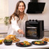 Salter black air fryer oven on kitchen counter, shown with assorted cooked meals
