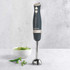 Grey Salter hand blender upright, next to bowl of green soup and peas, on countertop