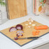 Bamboo chopping board with sliced red onion, carrot, garlic and a knife on a kitchen counter