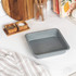 Grey non-stick baking trays set shown with cooked food on kitchen counter
