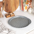 Grey non-stick pizza tray with holes, shown on kitchen worktop