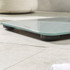 Silver digital bathroom scale with large blue-lit display, front view.