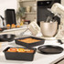 Black non-stick bakeware set with round, square, and loaf tins in a kitchen scene.