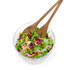 Glass bowl of mixed salad with wooden servers