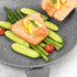 Cooked salmon fillet with lemon, asparagus, and vegetables in non-stick pan