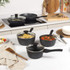 Set of black speckled non-stick saucepans and frying pan with lids in kitchen setting