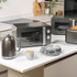 Stainless steel 2-slice toaster with toasted bread, shown next to plate with buttered toast.