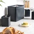 Matte grey electric kettle with chrome accents on kitchen counter next to tea and glasses