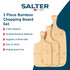 Set of three bamboo chopping boards with handles, displayed in a kitchen setting.