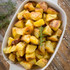 Roast potatoes with rosemary in white serving dish