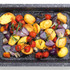 Roast potatoes, cherry tomatoes, red onion and rosemary in a speckled oven tray