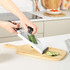 White handheld grater with black handle, shown on kitchen counter beside a vegetable sandwich.