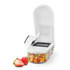 White vegetable chopper with diced fruit in container and fresh strawberries in front