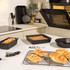 Set of black non-stick bakeware in a modern kitchen with fresh pastries and baked treats.