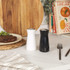 Salt and pepper grinders, one white and one black, on kitchen worktop
