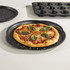Home baking pizza tray with cooked pizza and basil, shown on kitchen worktop
