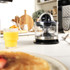 Black and silver electric citrus juicer with clear jug and handle, shown from front.