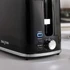 Black toaster with removable crumb tray, shown beside buttered toast. Product feature image.