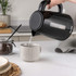 Black Salter kettle pouring hot water into a mug in a modern kitchen