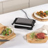 Open black electric grill with non-stick speckled plates shown flat for tabletop cooking
