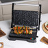 Open black electric grill with non-stick speckled plates shown flat for tabletop cooking