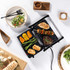 Tabletop electric grill cooking assorted meats and vegetables, shown in use.