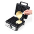 Black electric waffle maker with open lid, batter being poured onto plates