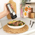 Hand holding Salter stainless steel electric grinder above mixed salad bowl on kitchen counter
