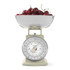 Cream kitchen scale with metal bowl filled with cherries, front view