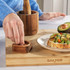 Salter wooden pestle and mortar set on bamboo board with avocado toast and seasoning.