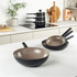 Set of three non-stick frying pans, black with taupe interior, shown on kitchen worktop