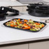 Set of black roasting trays with roast joint and vegetables on a kitchen counter