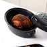 Roast joint in a black speckled enamel roasting pan with lid, shown on a kitchen counter.