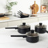 Set of three non-stick frying pans in black, shown on white kitchen worktop