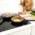 Two non-stick frying pans on an induction hob with cooked food, kitchen utensils in background