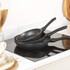 Set of three black speckled non-stick frying pans stacked on a kitchen hob