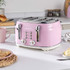 Pink 4-slice toaster with crumb tray partly open, beside plate of toast and pink mug