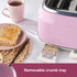 Pink 4-slice toaster with controls, two seeded bread slices toasting, hand pressing lever