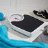 Mechanical bathroom scale with black platform on tiled floor