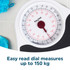 Person standing on analogue bathroom scale, black and white design, sports shoes and towel nearby