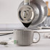 Grey electric kettle being switched on, highlighting illuminated power button feature