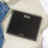 Black Salter digital bathroom scale with display, shown on tiled floor.