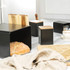Black bread bin set with wooden lids on kitchen counter, loaf of bread inside bin