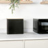 Black metal bread bin with wooden lid on kitchen worktop