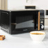 Black Salter microwave with wood-effect handle, shown on kitchen counter with hand opening door