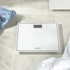 White Salter digital bathroom scale on tiled floor, shown from above.
