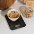 Black digital kitchen scale with ceramic bowl of granola, shown in use for weighing