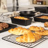 Black non-stick baking trays and tins with freshly baked cookies, croissants and bread on a kitchen counter