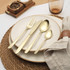 Set of four gold-coloured cutlery pieces: knife, fork, dessert spoon, teaspoon